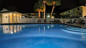 A swimming pool with a white fence, palm trees, and buildings in the background. - 4-Person Condo only a short walk to beach. (Destin)