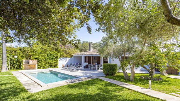 Un espace piscine doté d’une terrasse carrelée, de chaises longues et d’un petit bâtiment avec un toit également carrelé.