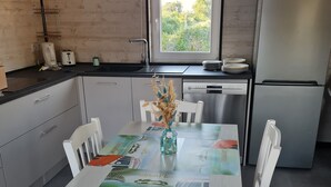 Eine moderne Küche mit weißen Schränken, einem Edelstahlkühlschrank und einem Fenster mit Blick auf Grünflächen.