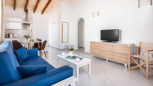 A modern living room with a blue sofa, a white coffee table, a TV, and a wooden cabinet. - Rimar 4, 2 bedroom apartment, Cap d´Artrutx (Cala´n Bosch)