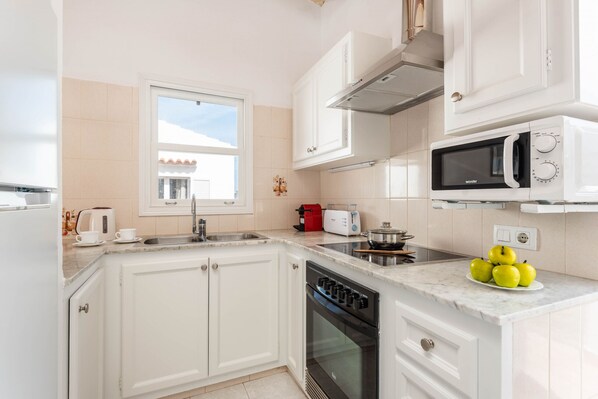 Een moderne keuken met witte kasten, een ingebouwde magnetron, een fornuis en een spoelbak.