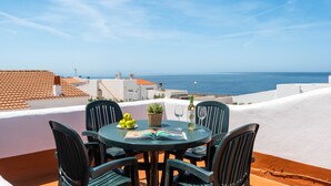 A round table with four chairs, a bottle of wine, a glass, and a book on a terrace overlooking the sea. - Rimar 5, 2 bedroom apartment, Cap d´Artrutx (Cala´n Bosch)