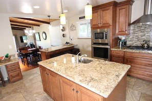 Enjoy cooking in this well-lit kitchen with a large island, stainless steel appliances, and wooden cabinetry.