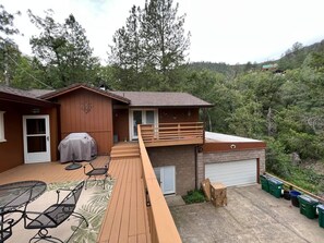Relax on the spacious deck with a barbecue grill, surrounded by trees and hills.