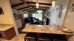 Una cocina con encimeras de granito, taburetes de madera y una isla grande.