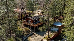 Una cabaña con terraza y garaje, rodeada de un bosque denso.