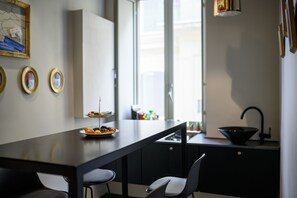 Ett modernt kök med en mörk bänkskiva, en diskho och ett fönster. På väggen hänger tre inramade tavlor.