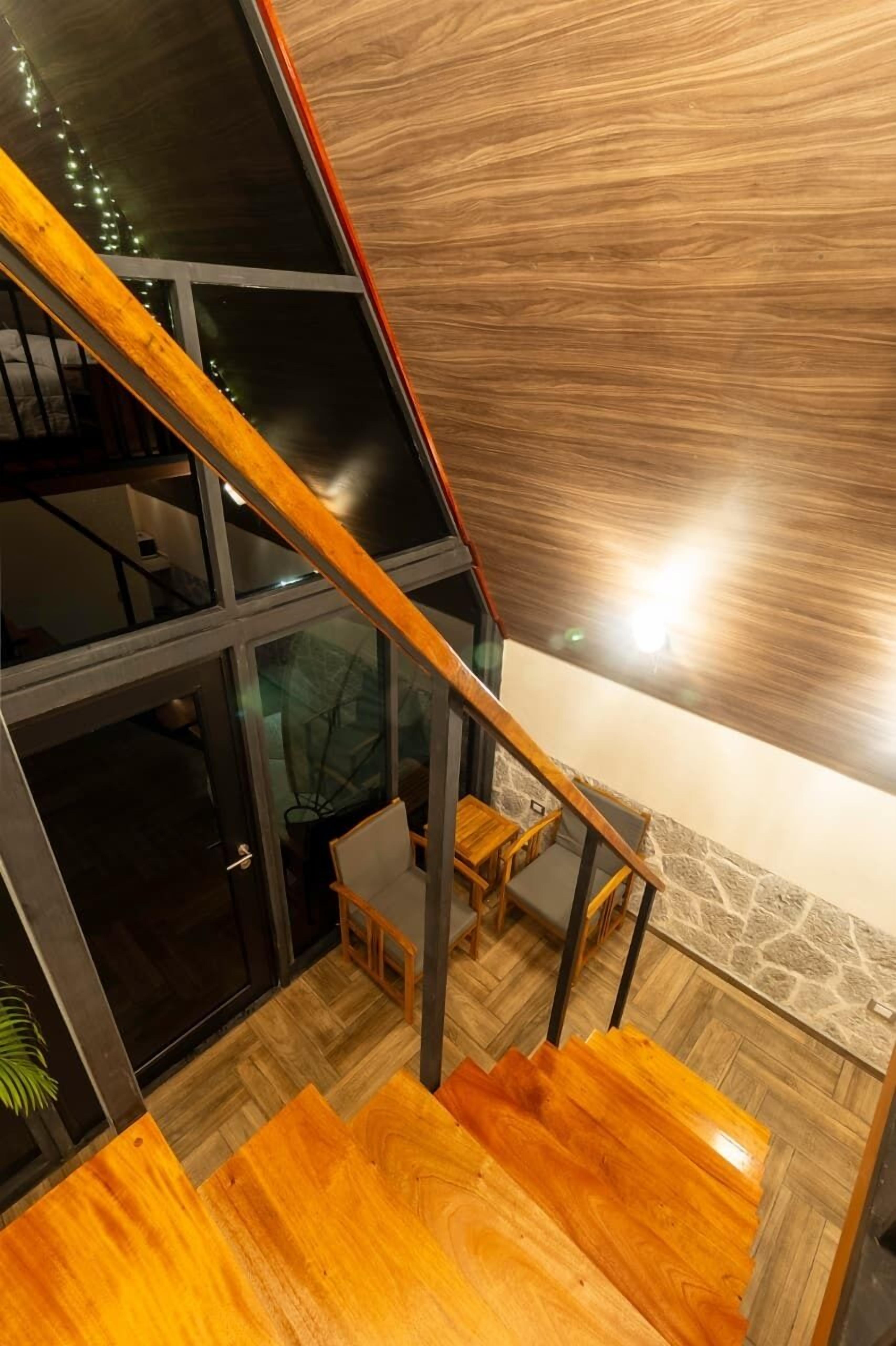 Un intérieur moderne avec un escalier en bois, un mur en pierre et une porte en verre donnant sur une autre pièce.