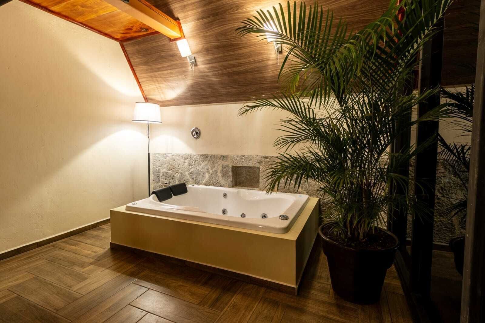 A modern bathroom with a freestanding bathtub, a stone accent wall, and a potted plant.