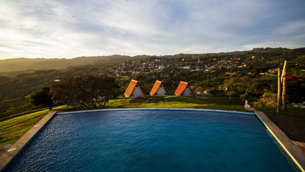 A swimming pool with a view of a town and hills in the background. - Villa de los Vientos (Cuetzalan del Progreso)