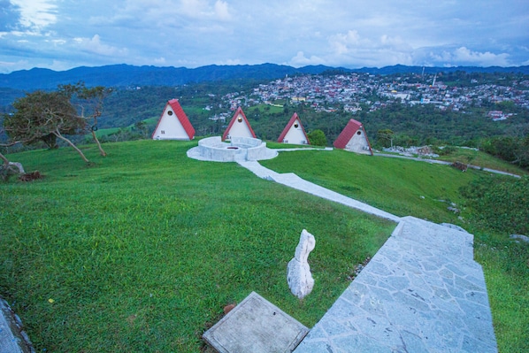 A grassy area with stone pathways leading to white houses with red roofs. - Villa de los Vientos (Cuetzalan del Progreso)