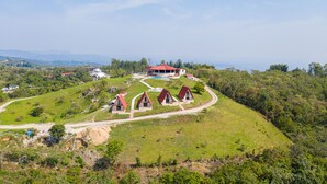 A hillside property with a main building and several smaller structures, surrounded by greenery and a clear sky. - Villa de los Vientos (Cuetzalan del Progreso)