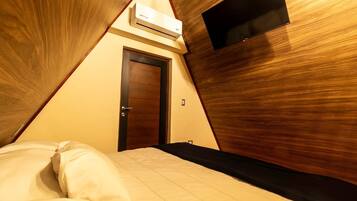 A triangular room with a bed, a door, and an air conditioning unit.