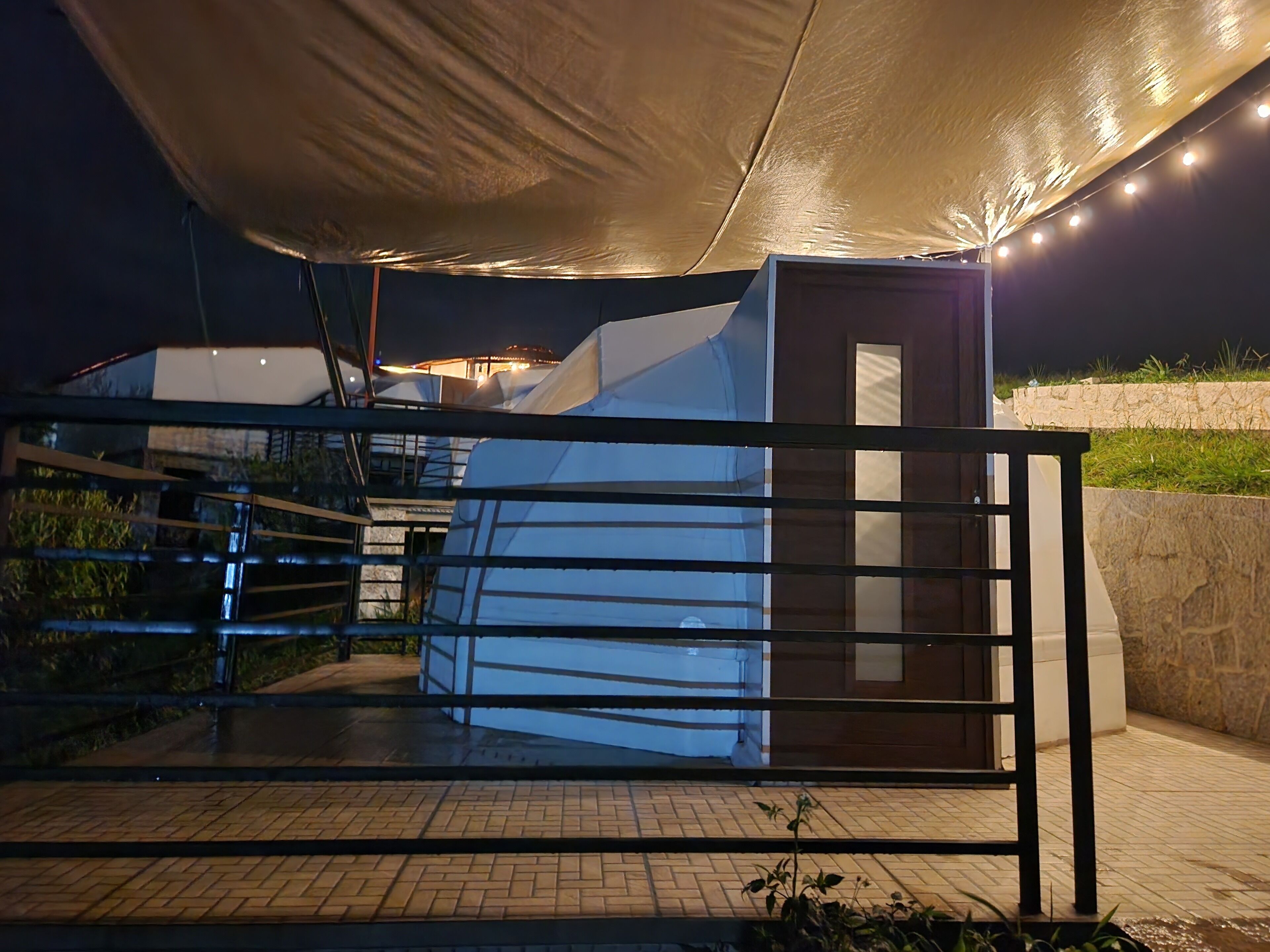 A modern building with a covered outdoor area, a staircase, and a gated entrance.