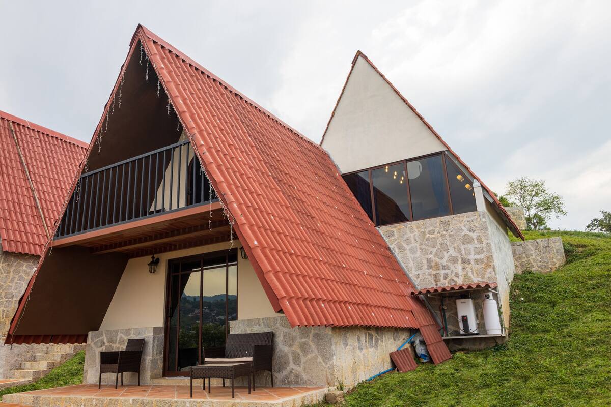 Una casa moderna con techo inclinado, paredes de piedra y un balcón.