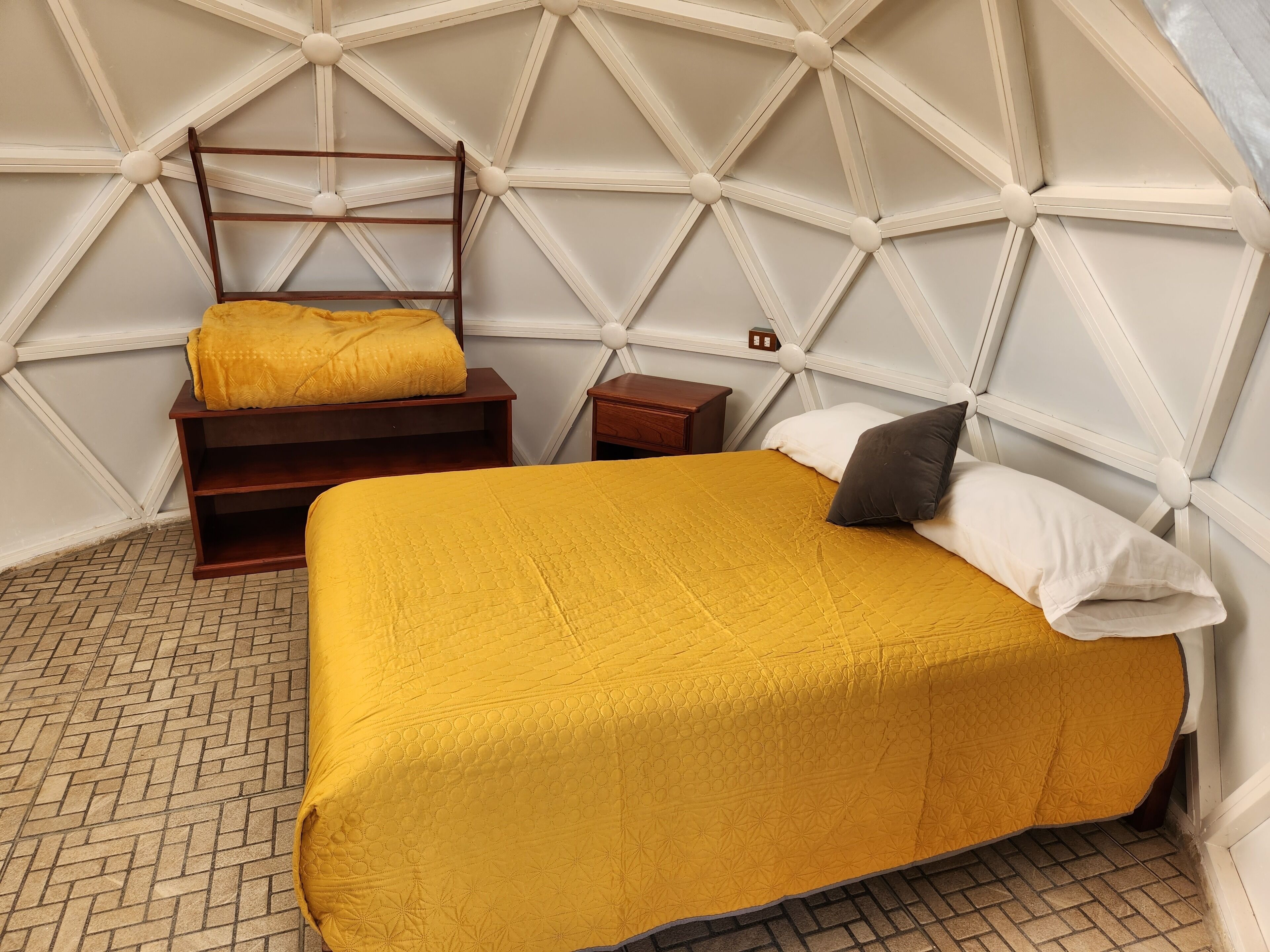 Ein Zimmer mit einem Bett, einer Holzleiter, einem Nachttisch und einem kleinen Holztisch.