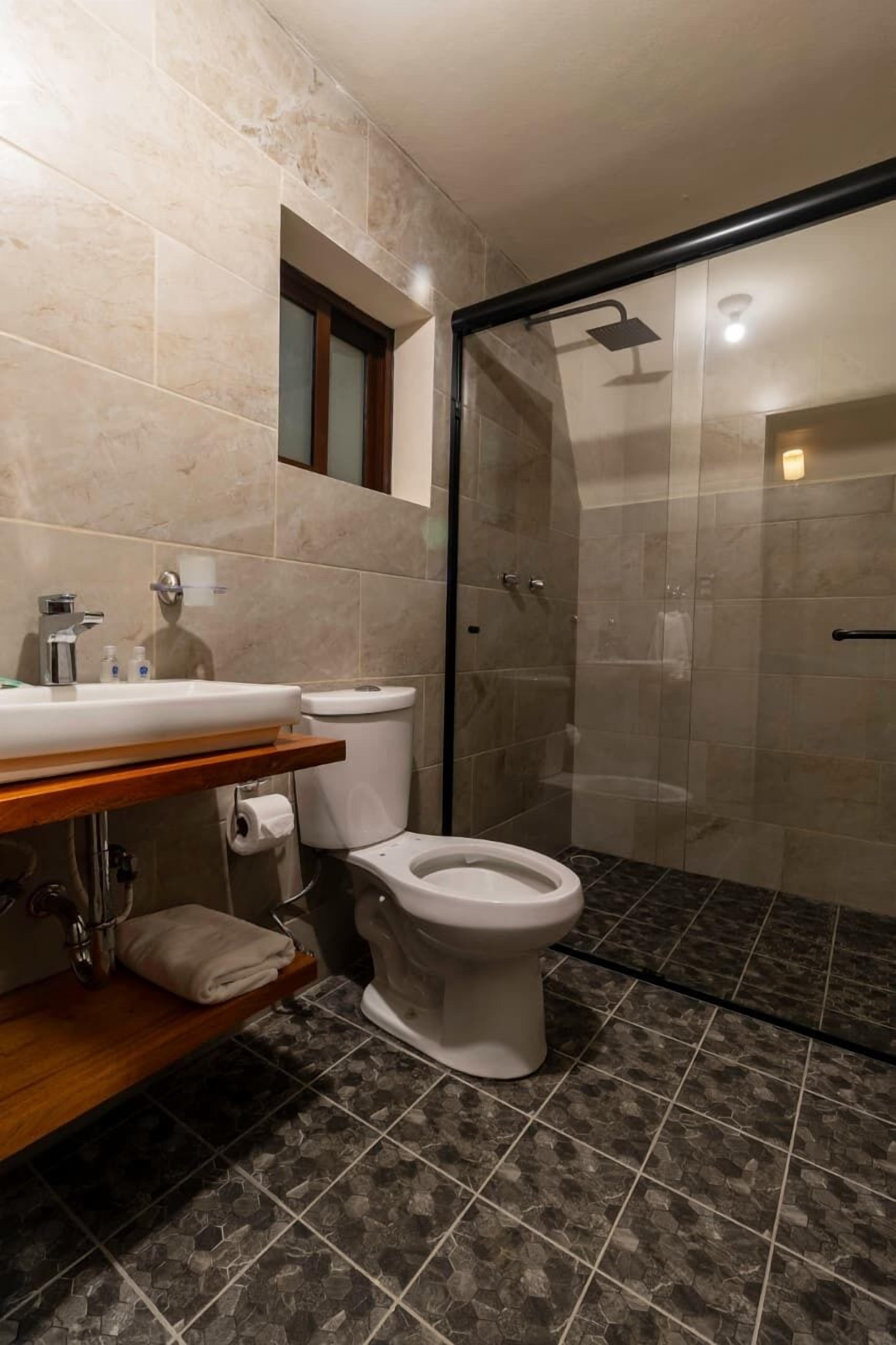 Et badeværelse med toilet, vask og bruseområde.