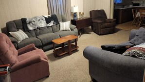 Una sala de estar con un sofá, sillones, una mesa de centro y un comedor con mesa y sillas.