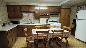 Una cocina compacta con armarios de madera, una mesa de comedor con sillas, una estufa y un refrigerador.