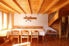 Un interior de madera con una mesa de comedor, sillas, una banca y una escalera.