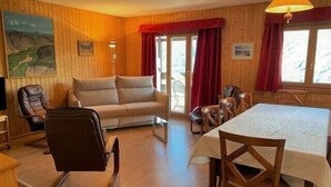 A cozy room with a sofa, chairs, a dining table, and a painting on the wall.