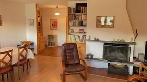 A cozy living room with a fireplace, wooden furniture, and a bookshelf.