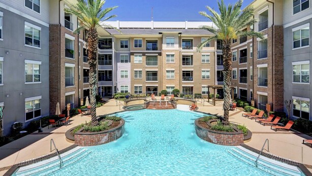 A multi-story hotel with a central swimming pool surrounded by lounge chairs and palm trees. - Luxury 2BD w/ pool. 5 min walk to NRG Stadium. 10 min Dr to Downtown Houston!! (Houston)