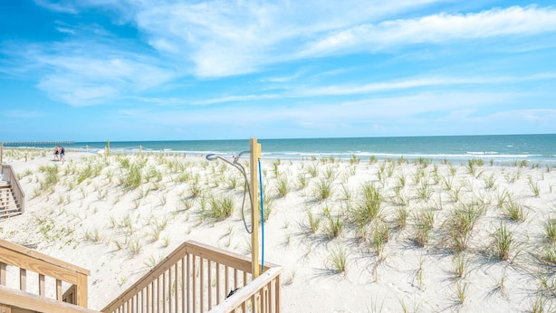 A beach with a wooden deck and a metal structure, likely a lifeguard stand, overlooking the ocean.