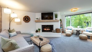 A modern living room with a fireplace, a large flat-screen TV, and a comfortable seating area. - Stunning & Modern Family-Friendly Slopeside Retreat in the Heart of Snowmass! (Snowmass Village)