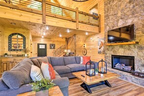 A spacious living area with a large sectional sofa, a stone fireplace, and a wooden ceiling. - Riverfront Blue Ridge Escape w/ Scenic Views! (Blue Ridge)