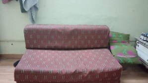 A small, simple room with a single sofa and a bed.