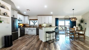 Una cocina moderna con armarios blancos, un refrigerador negro y piso de madera.