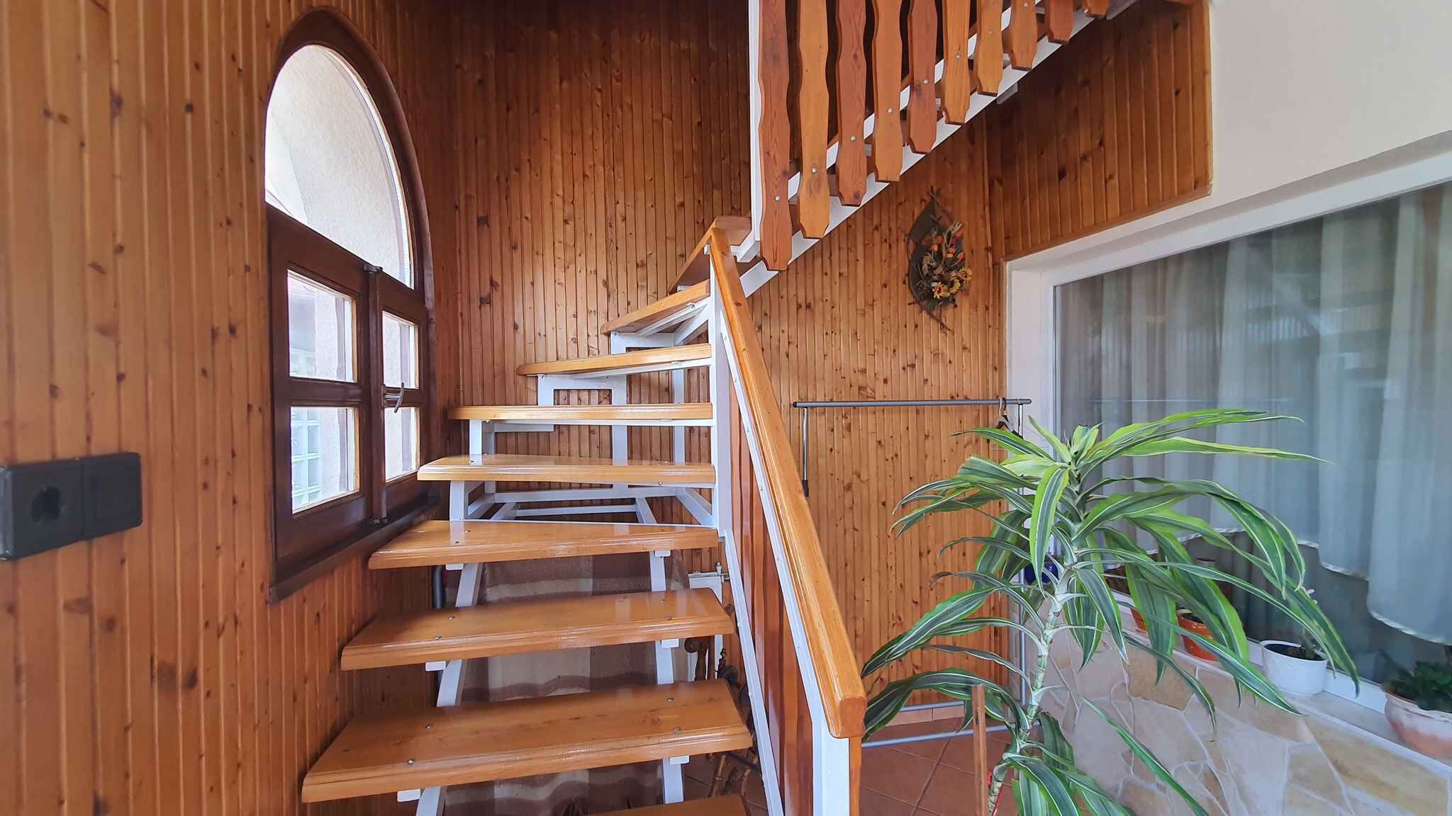 A wooden staircase with white railings leading to an upper floor.