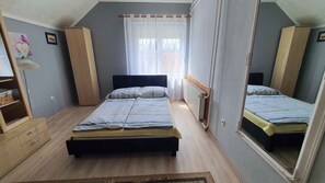A bedroom with two beds, a wooden wardrobe, a radiator, and a mirror. - Holiday apartment nicely furnished with Wi-Fi and air conditioning (Balatonlelle)