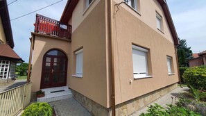 A two-story house with a red door, white window shutters, and a small balcony. - Holiday apartment nicely furnished with Wi-Fi and air conditioning (Balatonlelle)