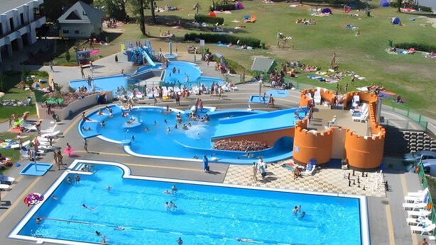 A large outdoor swimming pool with multiple lanes and a water slide.