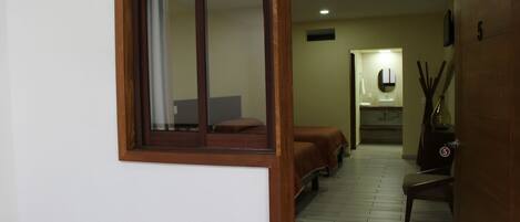 Una habitación de hotel con ventana de madera, una cama, una silla y una mesita.