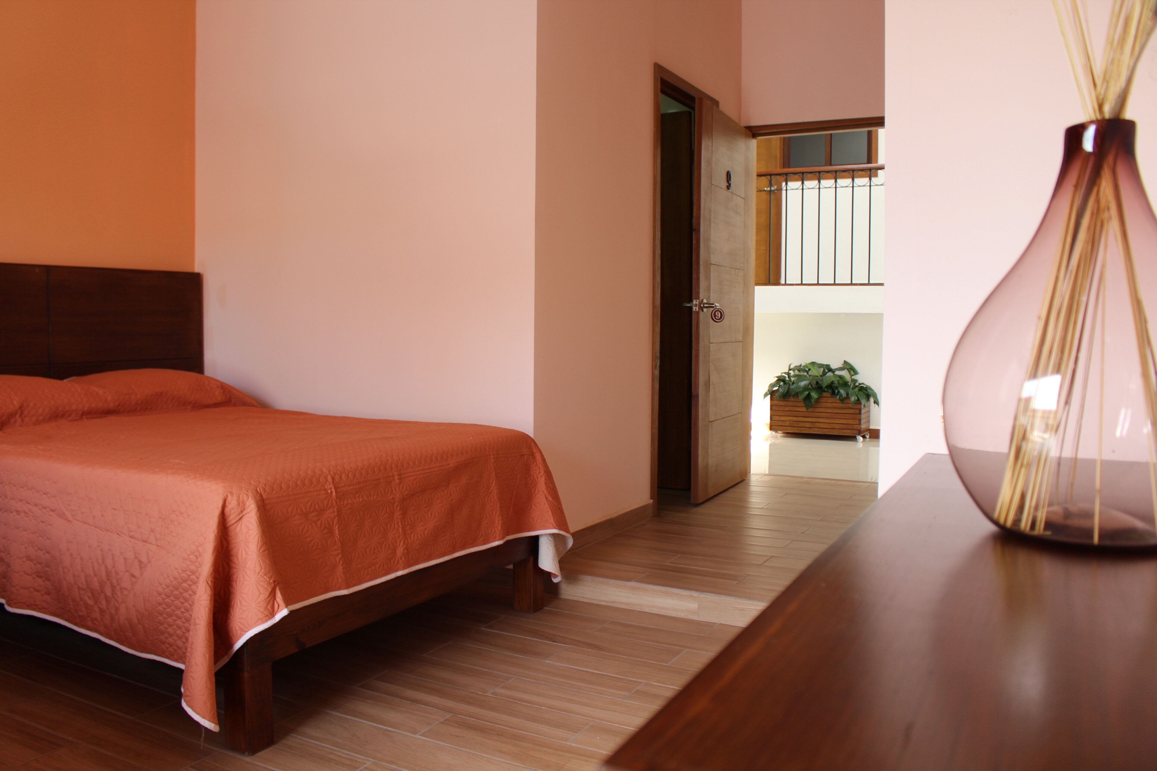 Un dormitorio con una cama de madera, una mesita de noche y un florero.