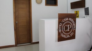 Un mostrador de recepción de hotel con un letrero de madera que dice "HOTEL CASA PERIGRA TAPALPA, JAL".