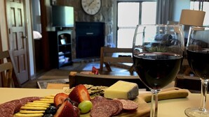 A charcuterie board with various meats, cheeses, and fruits, accompanied by glasses of red wine, set in a cozy room with a fireplace and a clock on the wall. - Heart of the mountain/5 Beds/Peaceful location with large deck (Gatlinburg)