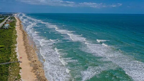Vista costera con playa de arena y olas del océano.