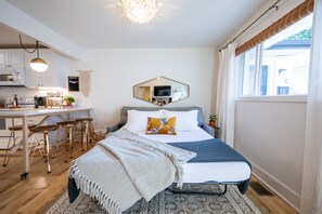 Una habitación pequeña con cama, un escritorio y un rincón de cocina.