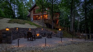 Una cabaña de troncos con chimenea de piedra, mobiliario exterior y una terraza de madera.