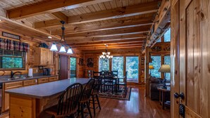 Interior de una cabaña de madera con cocina, comedor y una zona de estar acogedora.
