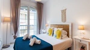 Ein Hotelzimmer mit Bett, zwei Nachttischen, einer Hängelampe, einem Fenster mit Vorhängen und Blick nach außen.