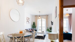 Ein modernes Wohnzimmer mit Essbereich, mit rundem Tisch, Stühlen, einer Couch und einem großen Fenster.