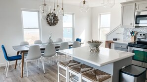 Una cocina moderna con armarios blancos, una isla central y un comedor con sillas.
