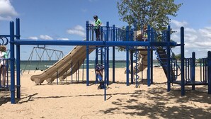Ein Spielplatz mit Rutsche und Klettergerüsten am Sandstrand.