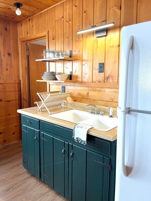 Compact kitchen with double sink, stainless steel faucet, and white countertop.