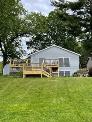 Enjoy a peaceful retreat in this two-story home with a spacious deck and stairs leading to the entrance.
